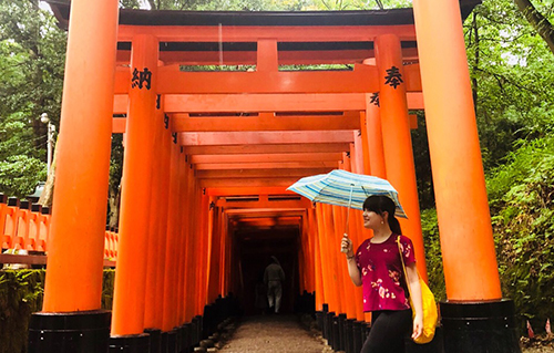 Student walking by Tori Shrines in Japan with umbrella